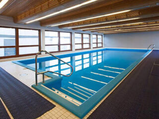 Indoor swimming pool with blue tiles and a step ladder