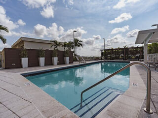 Refreshing hotel pool with clear blue water and lounging area under a bright Miami sky