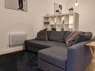 Minimalist and modern living room with a large gray sectional sofa, a white shelving unit displaying small plants