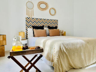Stylish bedroom with a boho-chic headboard, neutral linens, and wooden tray