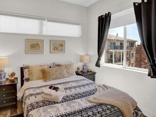 A well-lit modern bedroom with a queen-sized bed, contemporary artwork and a window with a view