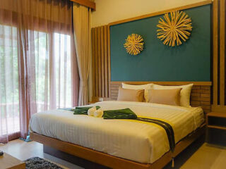 Modern bedroom with a large bed, wooden headboard and straw wall art in a Krabi hotel room