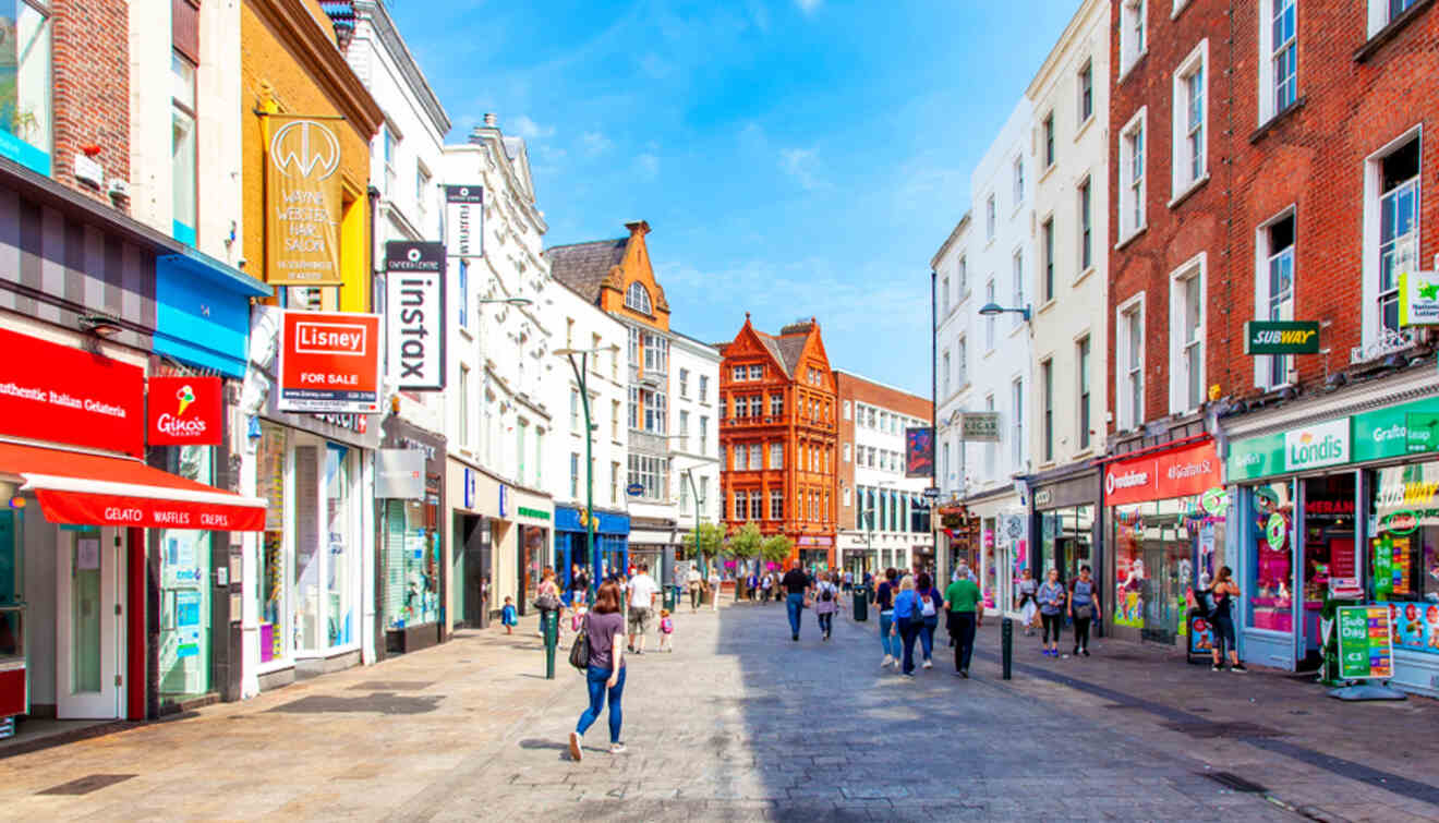 The lively Grafton Street in Dublin, showcasing a pedestrianized area with diverse shops and storefronts under a bright blue sky.