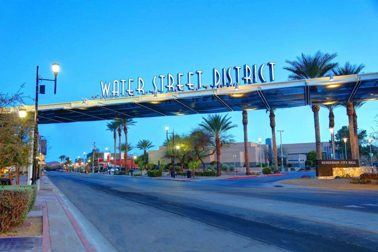 Twilight view of the Water Street District sign in Henderson, Nevada, with palm trees and the cityscape in the background