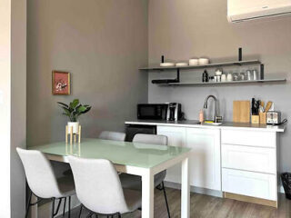 Minimalistic and sleek kitchen dining area in a modern studio with clean white surfaces and light gray chairs