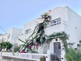 Charming exterior of a Villa draped in vibrant bougainvillea, with traditional white Cycladic architecture