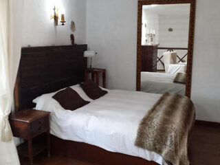 Traditional room decor with white walls, dark wood furniture, and a bronze-colored bedspread