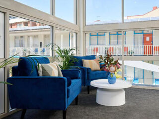 Blue couch and chair in front of large window with a coffee table with fresh flowers