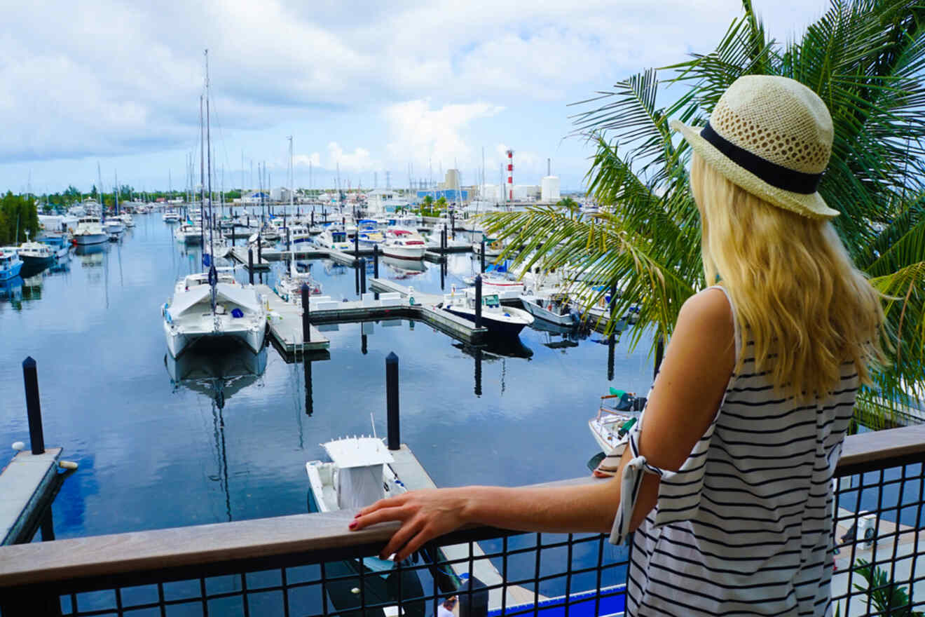 Blonde woman in a sunhat overlooking a marina filled with boats on a cloudy day in Key West
