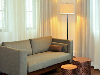 Cozy hotel lounge area with a minimalist gray sofa, floor lamp, and metallic side tables