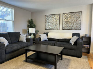 Cozy living room with a plush dark gray sofa set, black coffee table, and decorative wall art