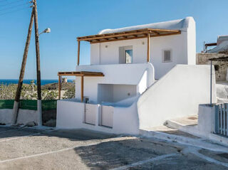 Charming white Cycladic exterior of a studio, with stone steps leading to the entrance