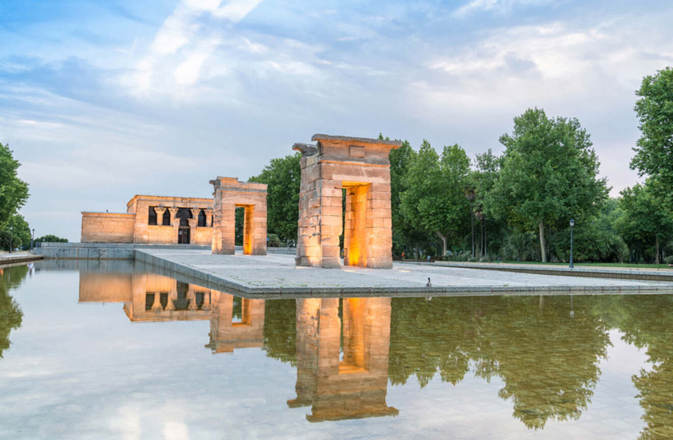The ancient Egyptian Temple of Debod in Madrid, illuminated at twilight with a tranquil reflecting pool