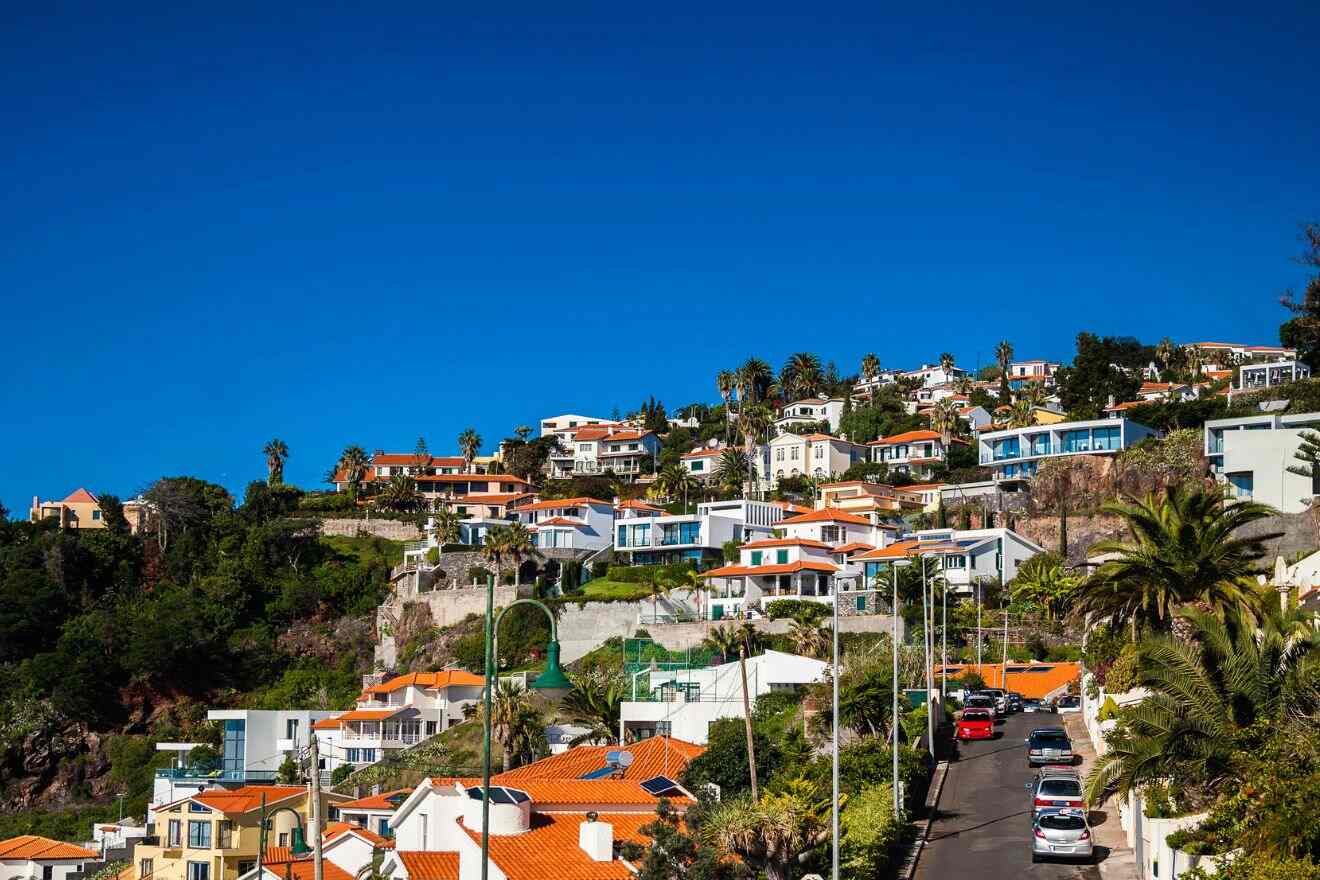 The terracotta rooftops of Madeira's hillside houses, with their varied architecture nestled among greenery, against a deep blue sky