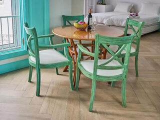 A quaint dining area with green-painted chairs and a wooden table, set on a tiled floor