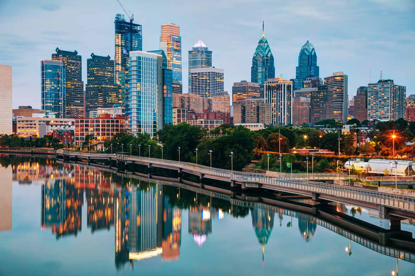 Evening view of Philadelphia skyline reflecting in the Schuylkill River, featuring prominent skyscrapers and lit-up buildings at dusk