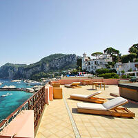 A spacious terrace with sun loungers and stunning views of the sea and surrounding hills in Capri.