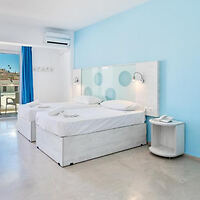 A bright and modern twin bedroom decorated in white and blue with a balcony.