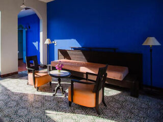 A spacious room with blue walls, patterned tile floor, and a mix of traditional and modern furniture