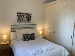 A simple bedroom with a double bed, white linens, and small bedside tables with lamps.