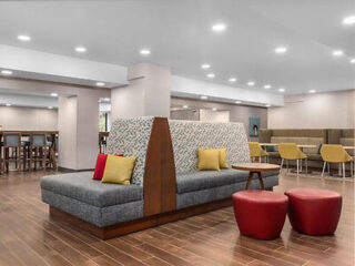 A spacious lounge area with modern seating, bright lighting, and a mix of colorful cushions and stools