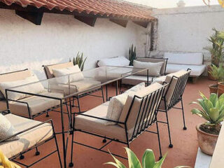 An inviting outdoor terrace with cushioned chairs, a glass table, and potted plants.