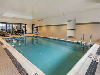 An indoor swimming pool area with lounge chairs and a clean, inviting pool.