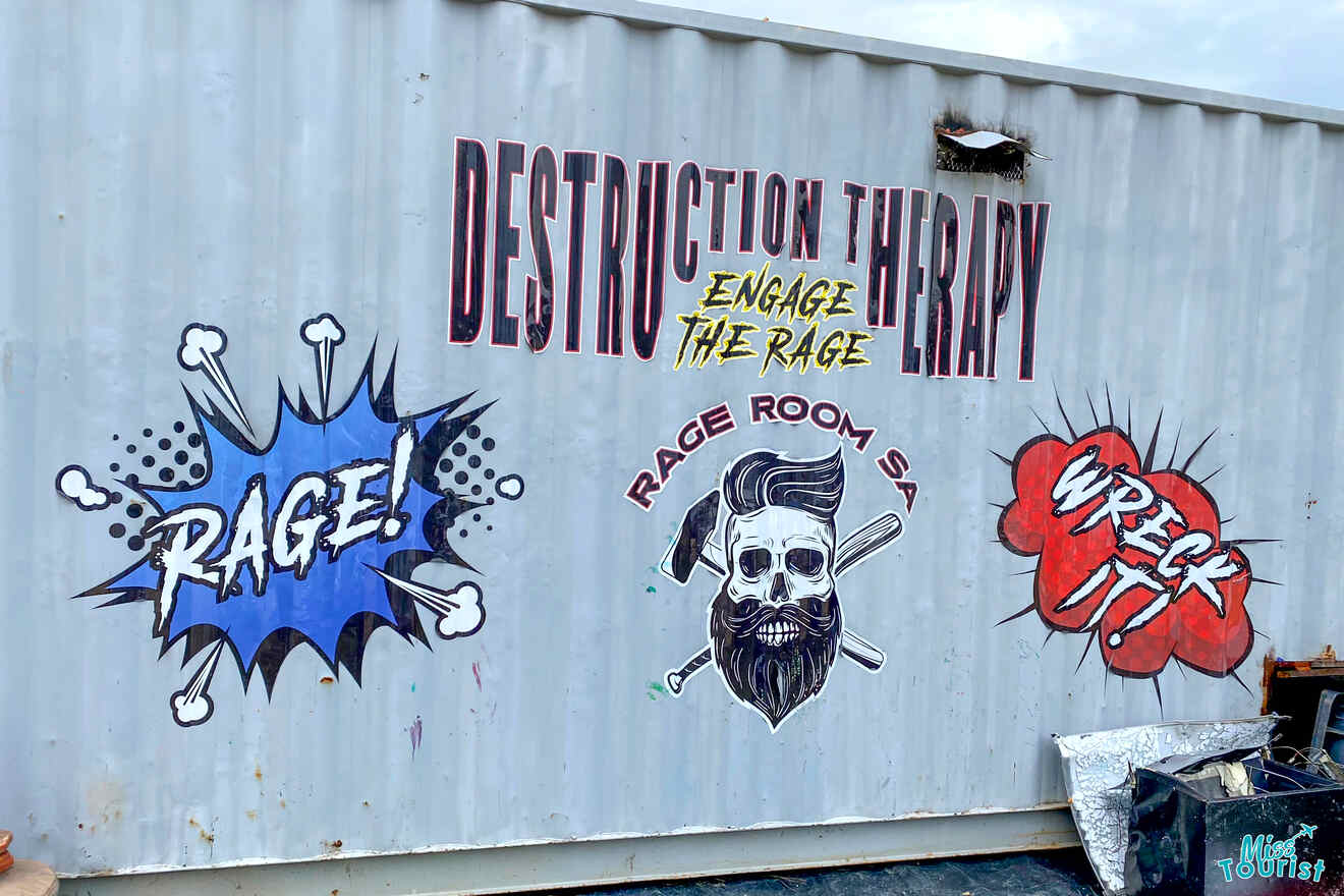 A metal container wall with the text “DESTRUCTION THERAPY: ENGAGE THE RAGE” and graphics depicting a bearded skull, comic-style "RAGE!" and "WRECK IT!" slogans.