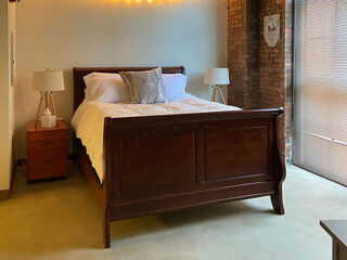 A spacious bedroom with a wooden bed frame and warm, ambient lighting.