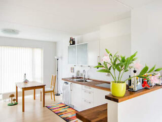 A clean, modern kitchen and dining area with white cabinets, a small table, and vibrant decorations.