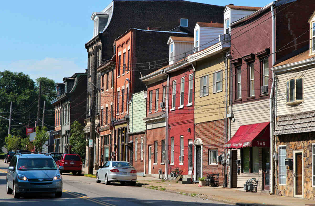 A vibrant neighborhood street lined with colorful row houses and cars parked along the road.