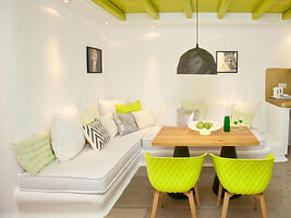 A bright dining area with a wooden table, vibrant green chairs, and a cozy built-in bench.