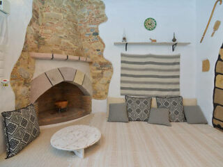 A cozy seating area with floor cushions, a rustic fireplace, and decorative items on the wall.