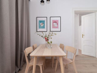 A minimalist dining area with a wooden table, matching chairs, and framed artwork on the wall.