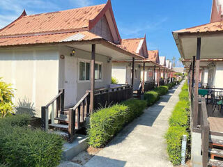 A row of quaint bungalows with small porches and a pathway in between.