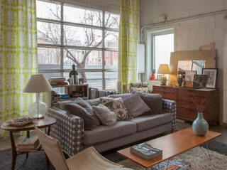 A cozy living room with a grey couch, patterned cushions, and eclectic decor.