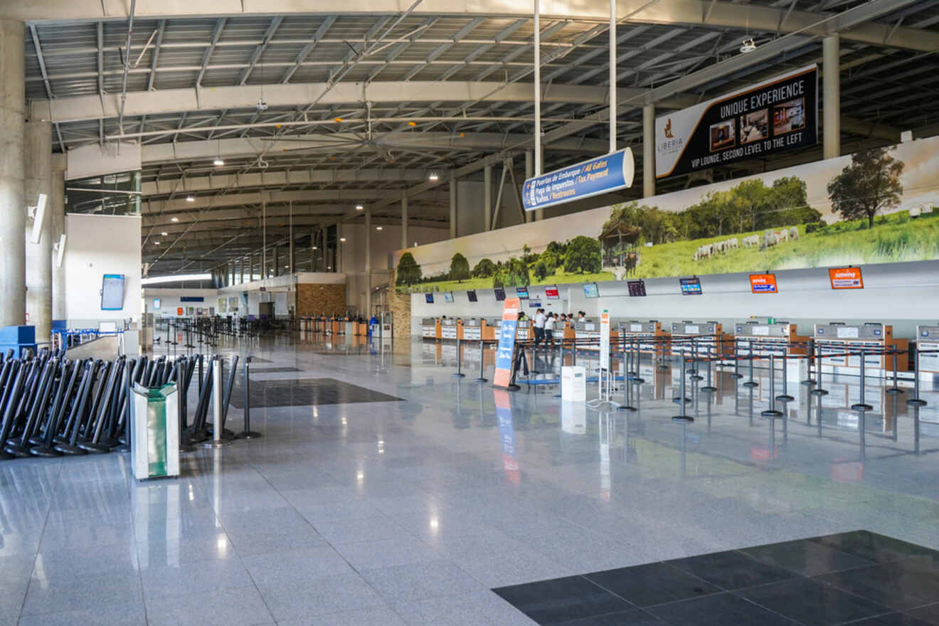 An empty check-in area at Juan Santamaria International Airport with ticket counters and informational signs.