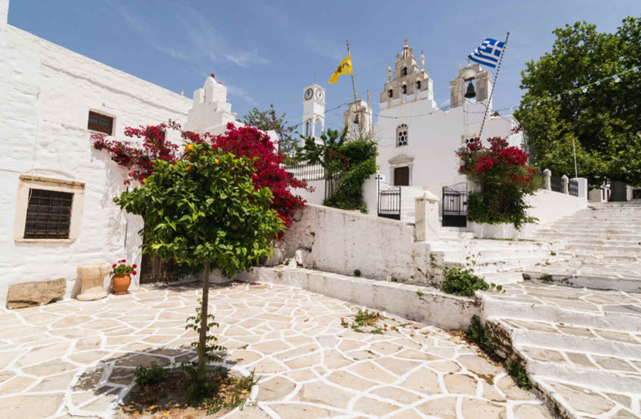 A charming village with white buildings, vibrant flowers, and flags, showcasing traditional architecture.
