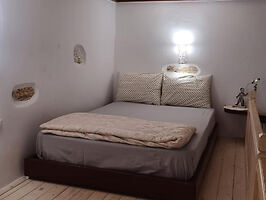 A compact bedroom with a double bed, neutral decor, and soft lighting, creating a cozy atmosphere.