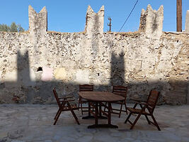 An outdoor dining area with wooden furniture set against an ancient stone wall, providing a historic feel.