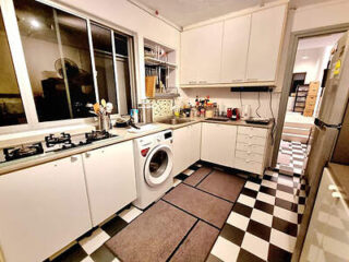 A bright kitchen with white cabinets, checkered floor, and modern appliances including a washing machine