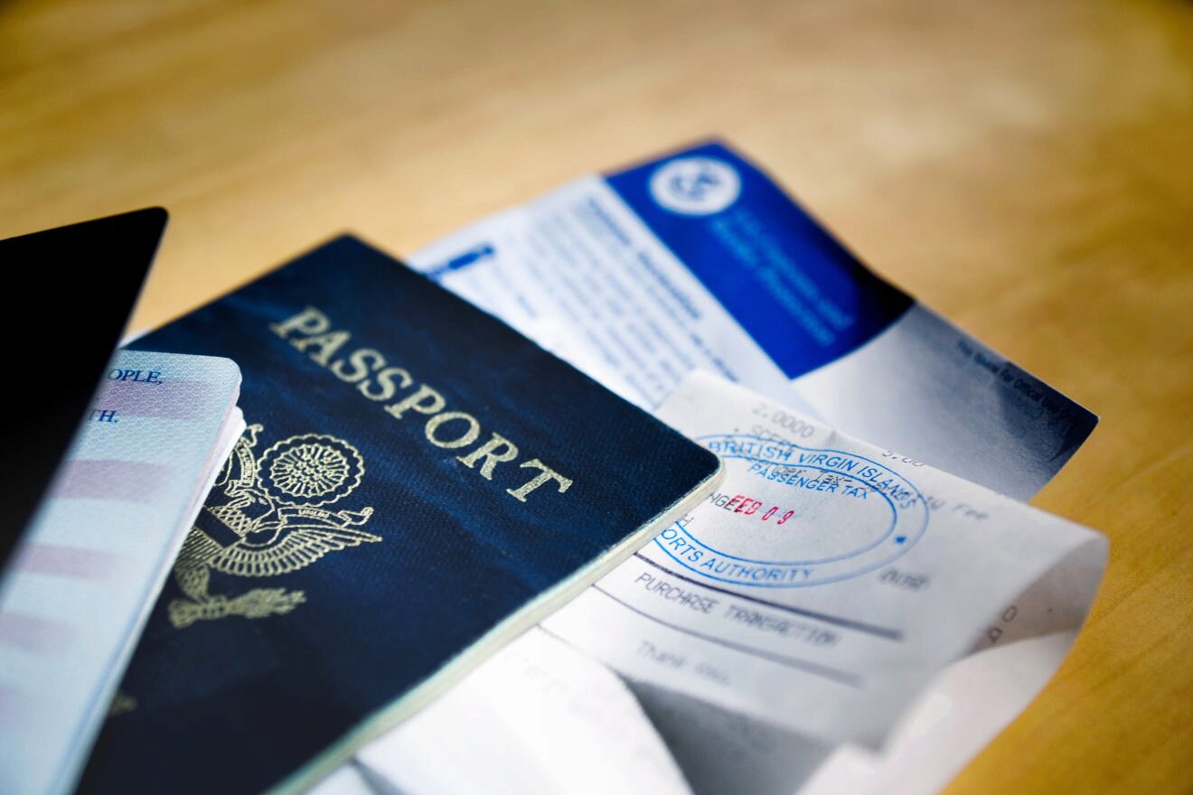A close-up of a U.S. passport with various travel documents and a boarding pass partially visible on a wooden surface.