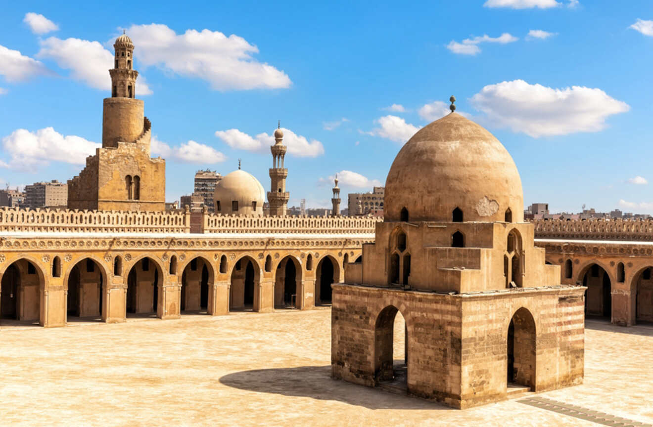 Historical mosque courtyard with domes and minarets against a blue sky.