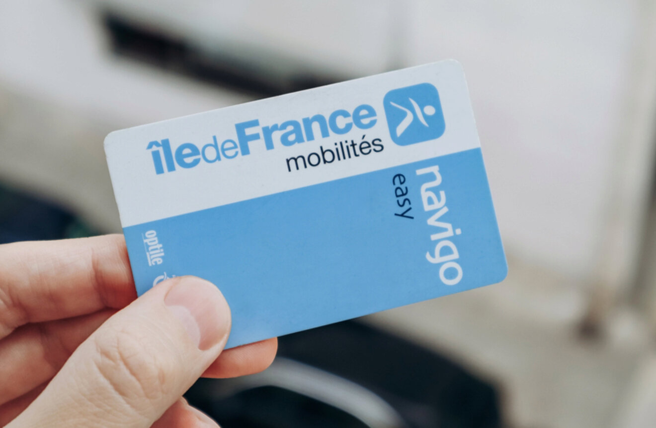 Hand holding a Navigo transportation pass card with "Île de France mobilités" written on it.