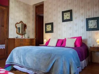 A cozy bedroom with a large, soft bed, colorful pillows, and classic decor elements
