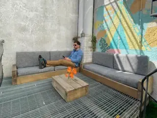 A modern outdoor lounge area with comfortable gray sofas and a colorful mural in the background
