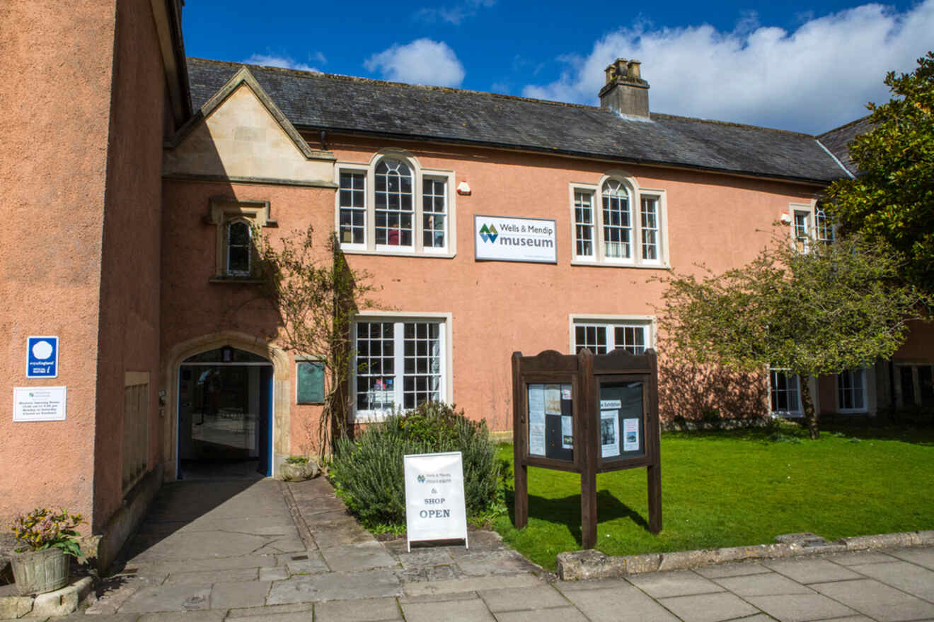 The Wells & Mendip Museum building with a sign indicating it's open to visitors.