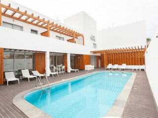 A modern outdoor pool area with white lounge chairs and wooden pergolas, providing a relaxing atmosphere