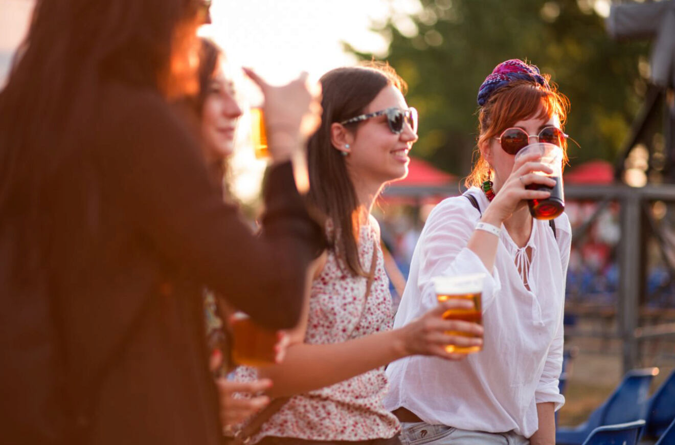 Group of friends enjoying drinks outdoors, each holding a glass of beer and smiling, suggesting a relaxed social setting