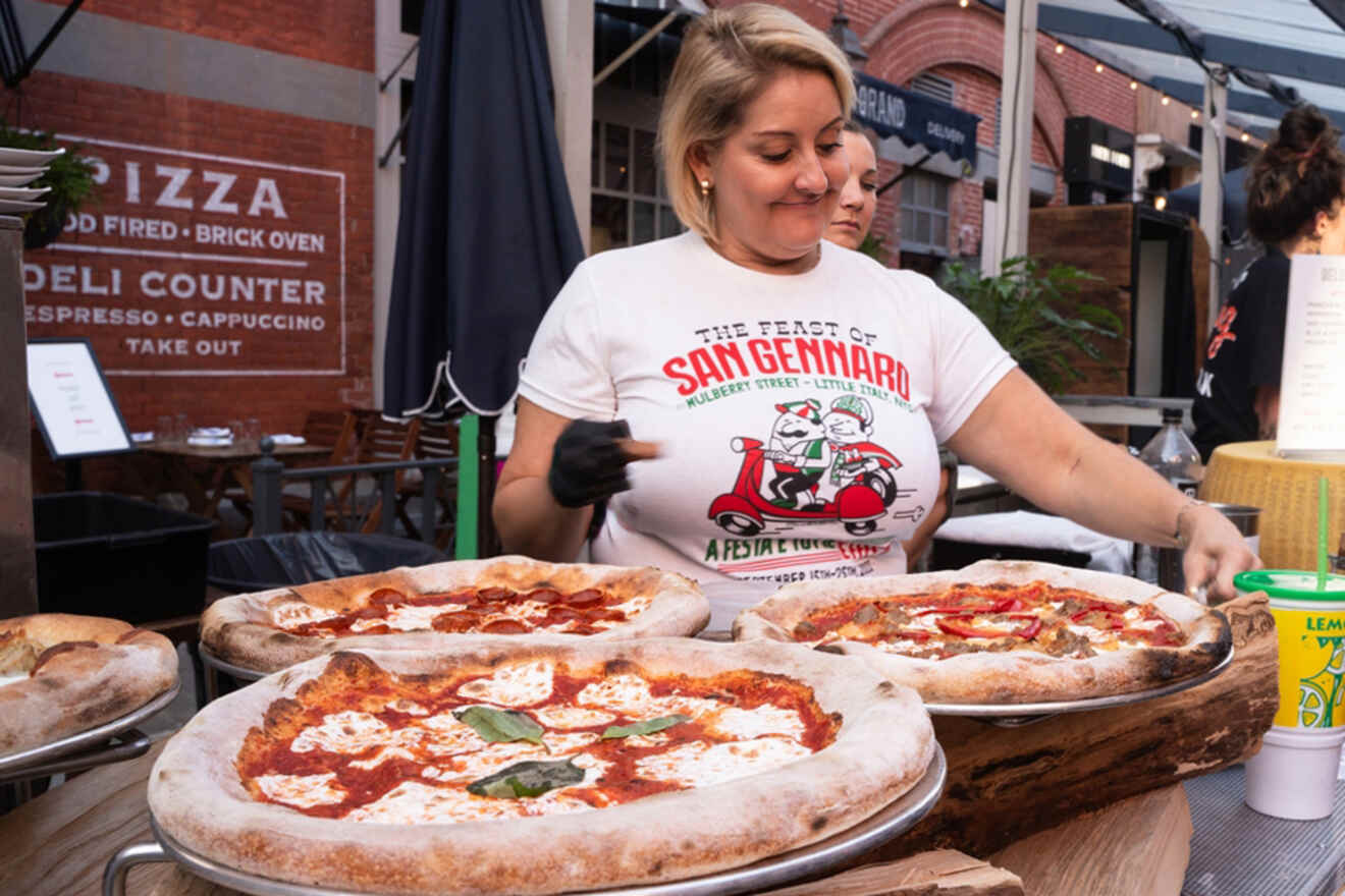 Woman serving large pizzas at the Feast of San Gennaro festival in New York City, USA.